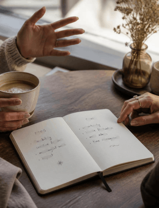 hands writing together over notes